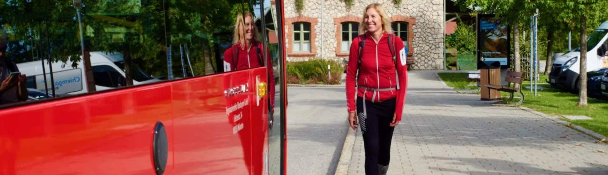 Frau mit Rucksack geht zum roten Bus | © DAV/Michael Vitzthum