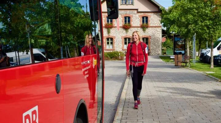 Frau mit Rucksack geht zum roten Bus | © DAV/Michael Vitzthum